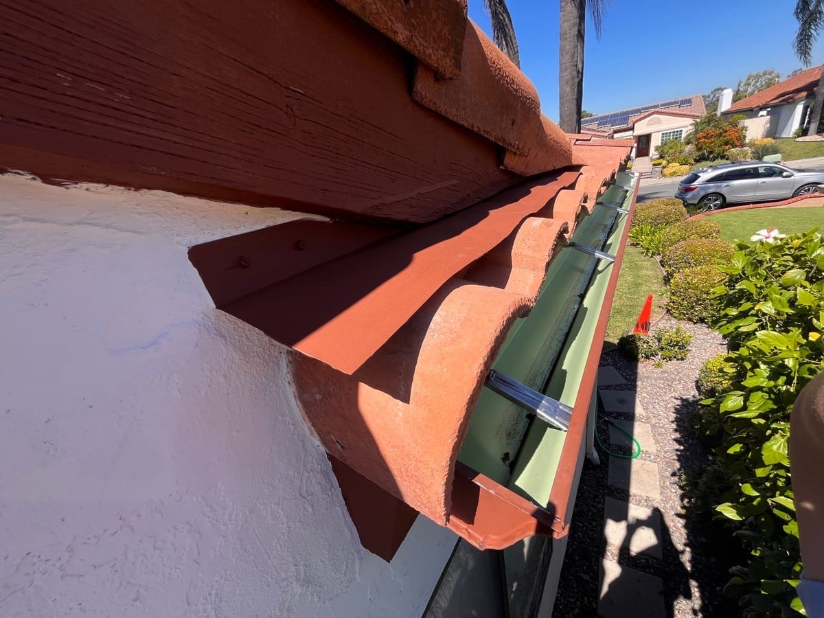 Rolled metal gutter installation with hidden mounts on an AWC project